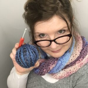 Picture of Sylvia Becker holding a crochet hook and a blue ball of yarn