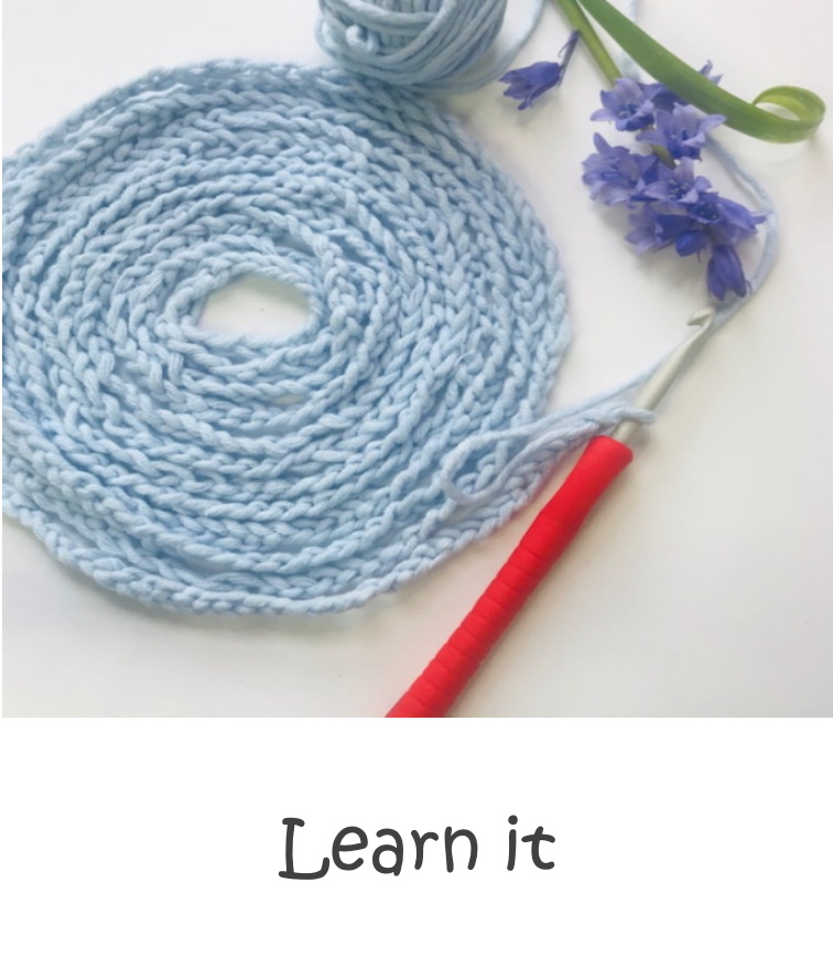 A blue crochet chain with a crochet hook and a purple flower.