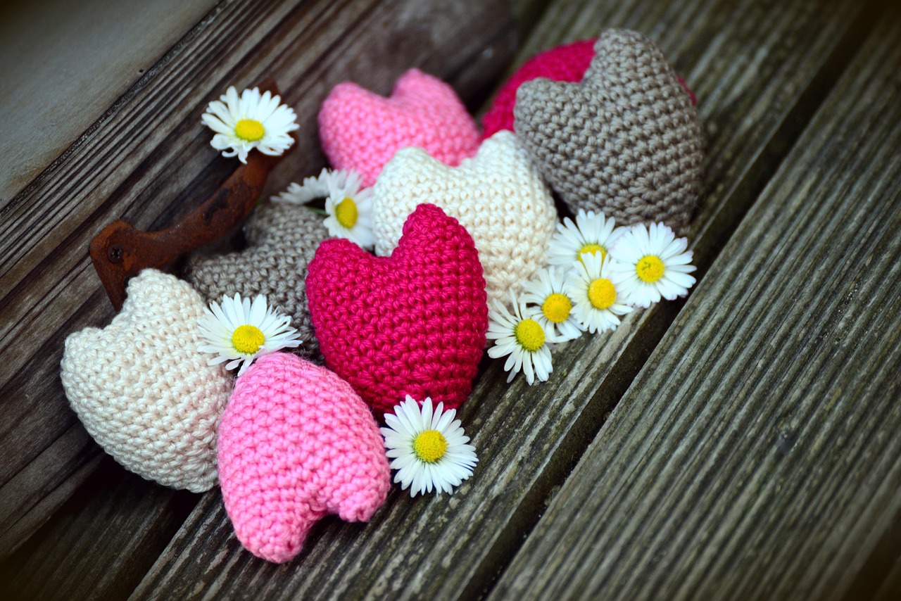Crochet hearts with real daisies on wooden planks